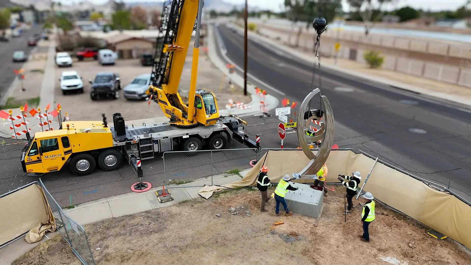 Aerial view of a crane setting equipment beside a busy street