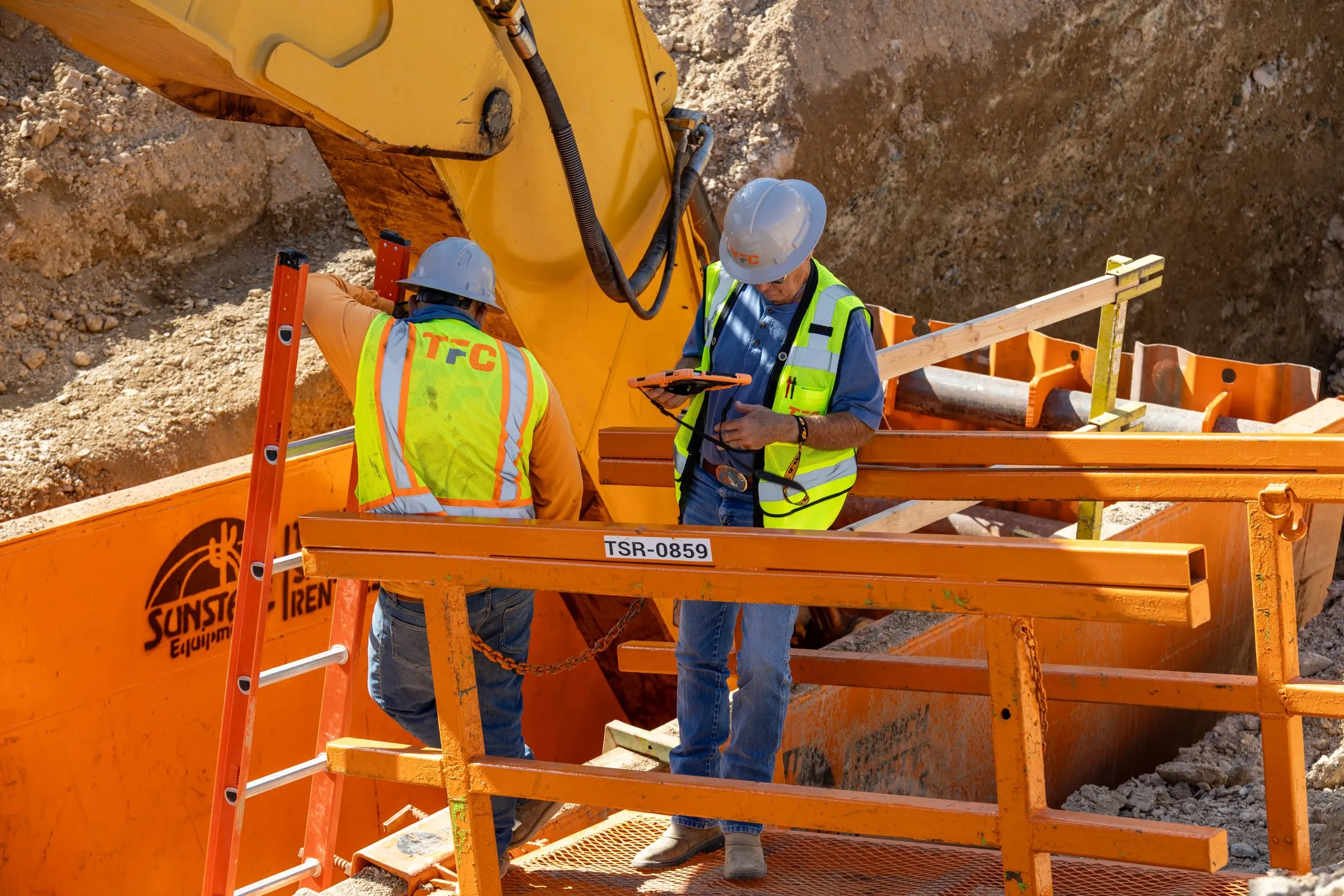 Construction crew reviewing plans in a trench box